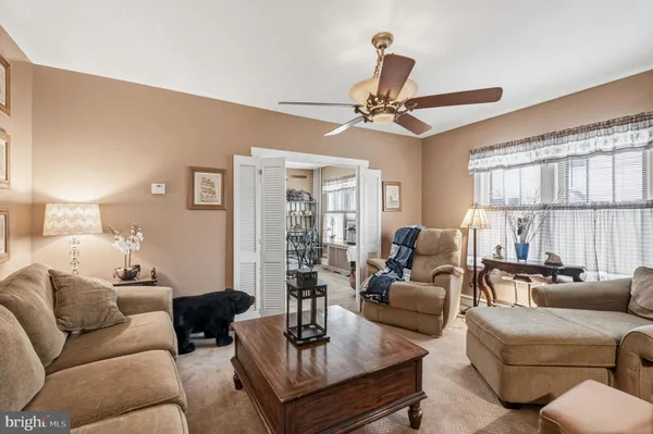 a living room with furniture a ceiling fan a lamp and a window