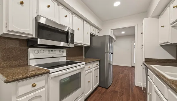 a kitchen with stainless steel appliances white cabinets white stove a sink and dishwasher