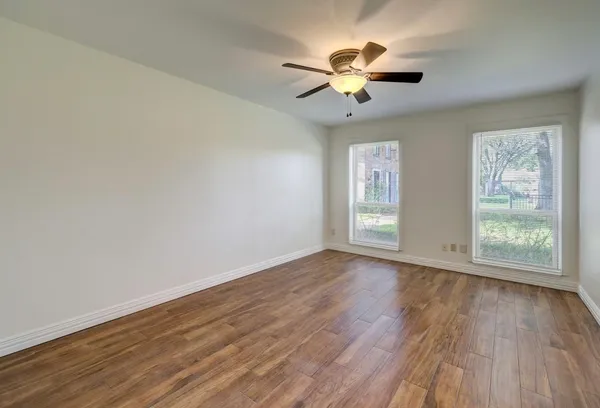 a view of an empty room with wooden floor and a window