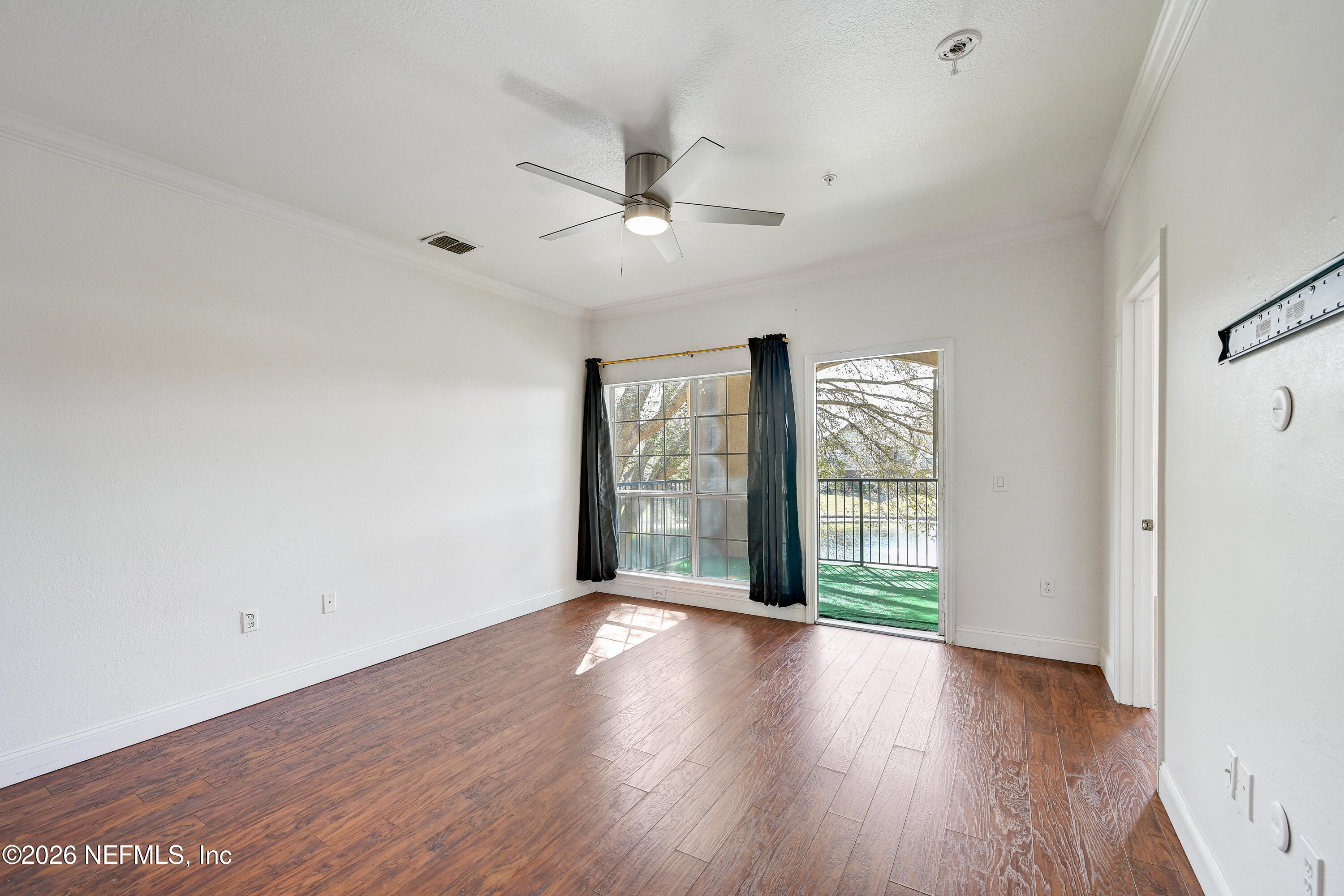10961 Burnt Mill Road, Unit 824 Jacksonville, FL 32256 - Photo 10 of 35 a view of an empty room with wooden floor and a window