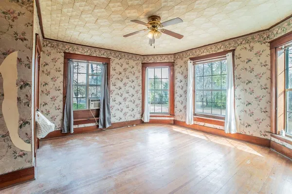 an empty room with chandelier fan and windows