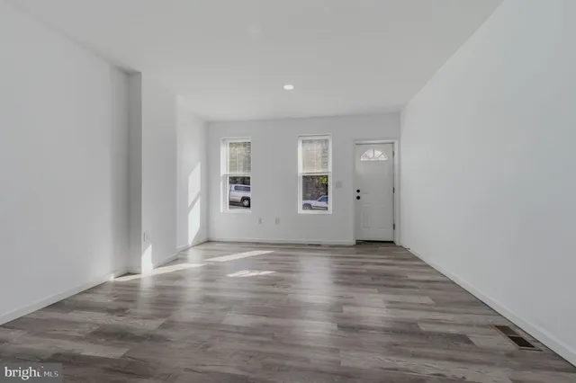 a view of an empty room with wooden floor and windows