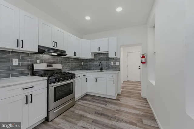 a kitchen with stainless steel appliances white cabinets and stove top oven