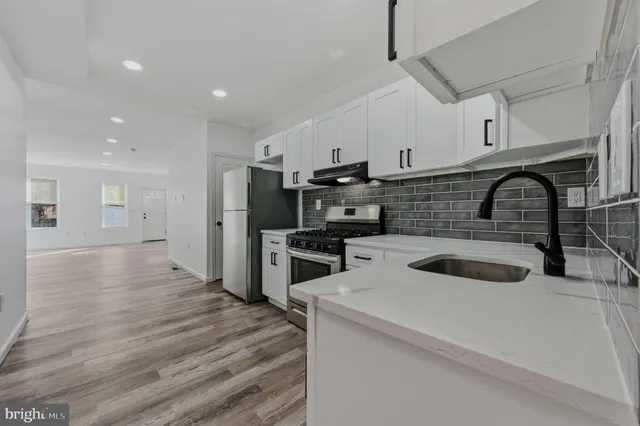 a kitchen with kitchen island stainless steel appliances a sink a stove and oven