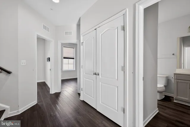 a view of a hallway with wooden floor and closet area