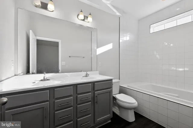 a bathroom with a toilet a sink a mirror a bathtub and shower