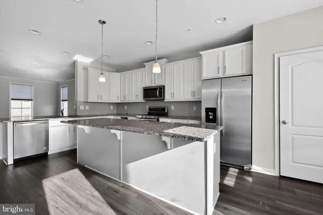 a kitchen with kitchen island a counter space a sink appliances and cabinets