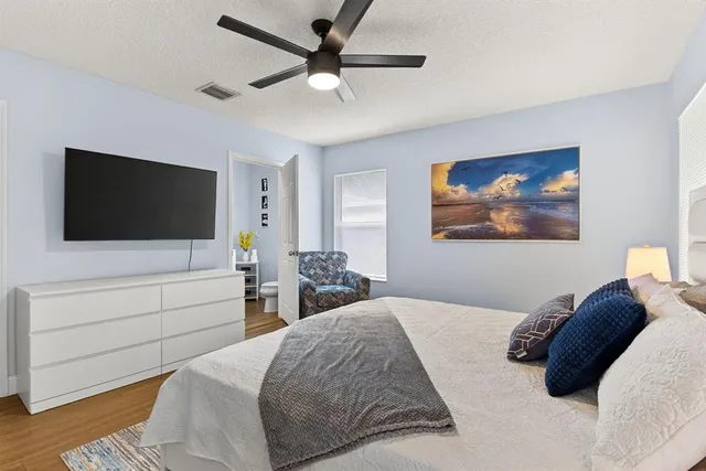 a bedroom with a bed a tv and wooden floor
