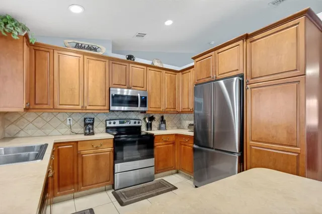 a kitchen with stainless steel appliances granite countertop a refrigerator stove top oven and sink