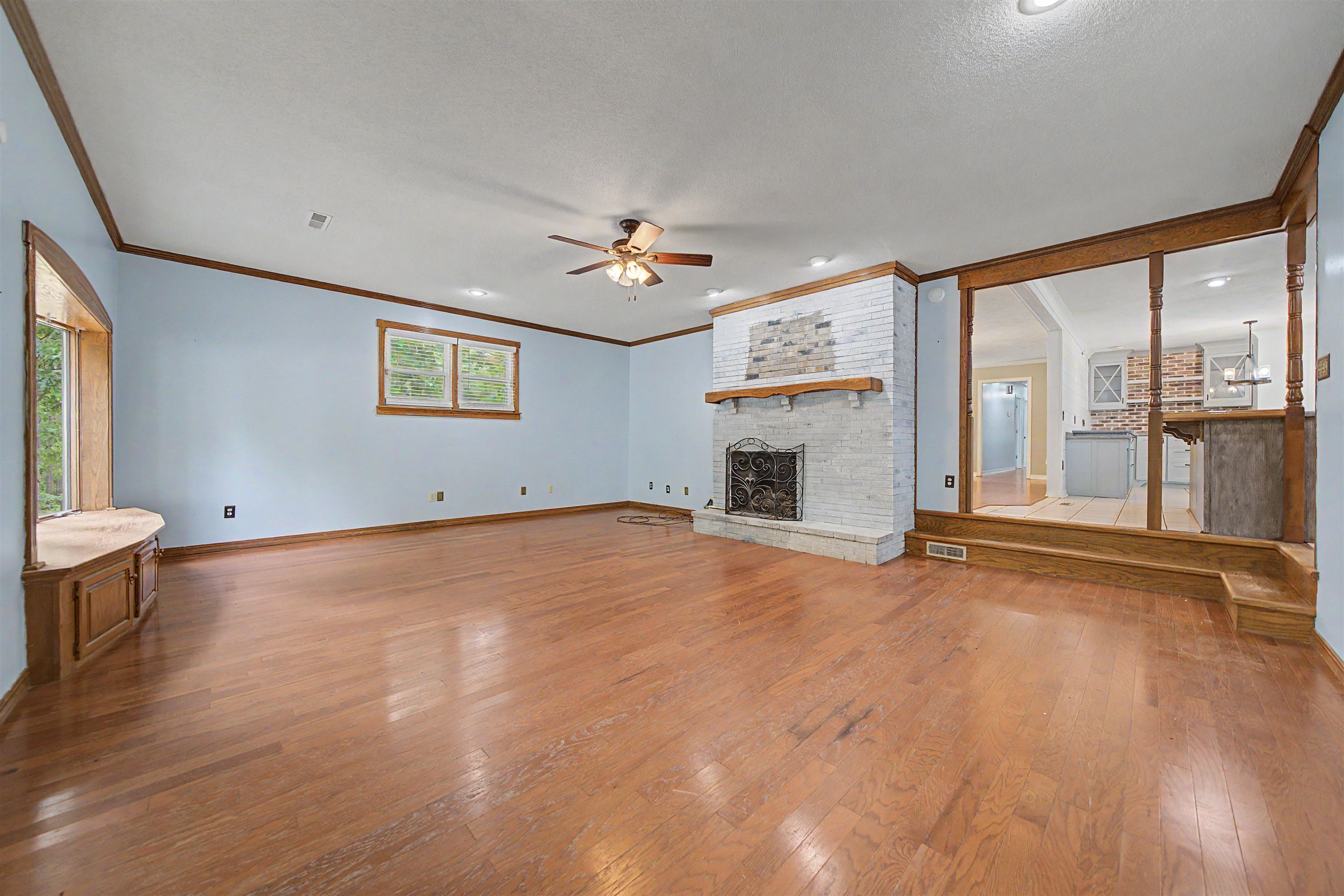 436 Skyline Road Selmer, TN 38375 - Photo 30 of 40 Expansive living area featuring wood-finish flooring, a white brick fireplace with a wood mantle, and a built-in window seat
