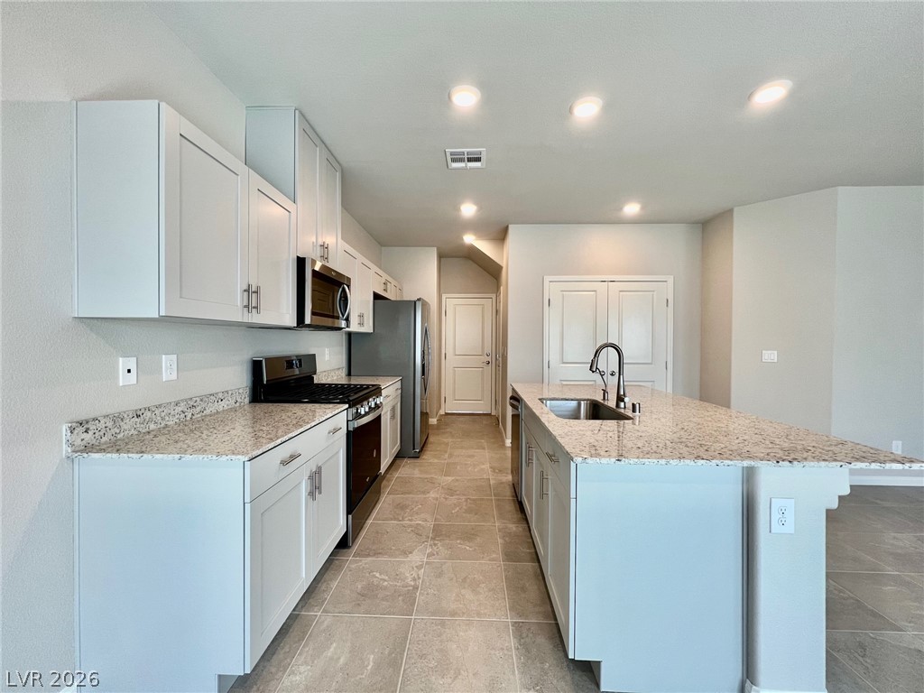 7845 Morganite Avenue Las Vegas, NV 89113 - Photo 5 of 21 Culinary creations come to life in this kitchen, featuring an island with a sink, sleek countertops, and modern appliances.