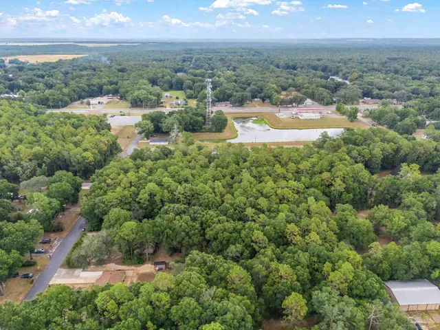 an aerial view of a houses with outdoor space and trees all around