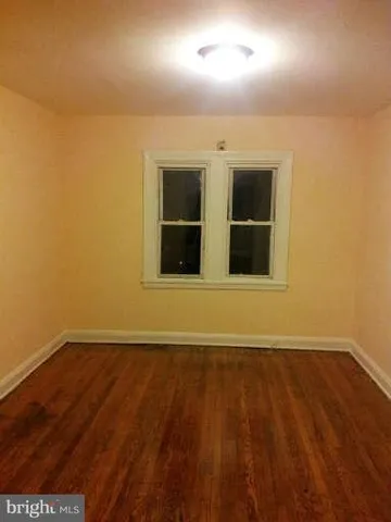 a view of an empty room with wooden floor and a fireplace