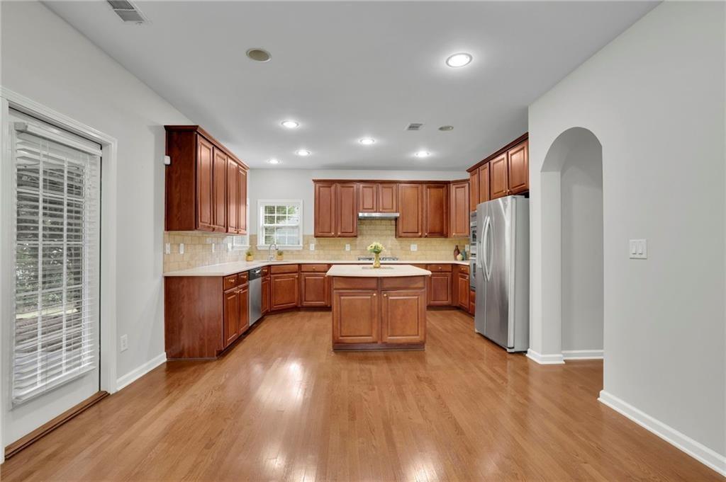 2945 Links View Way Cumming, GA 30041 - Photo 13 of 25 a large kitchen with stainless steel appliances granite countertop a refrigerator a sink dishwasher a oven with wooden cabinets and wooden floor