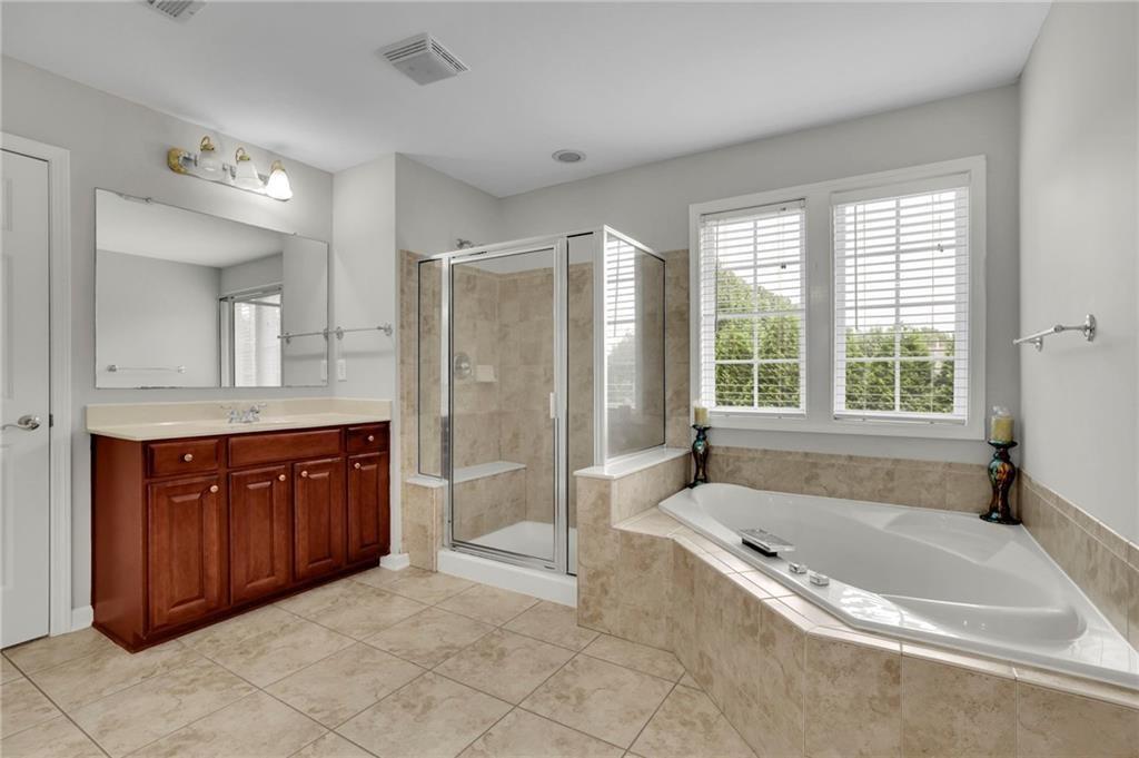 2945 Links View Way Cumming, GA 30041 - Photo 18 of 25 a spacious bathroom with a granite countertop tub sink shower and mirror
