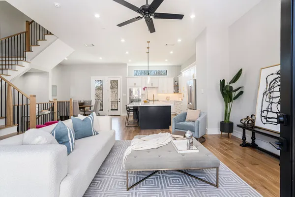 a living room with furniture kitchen view and a chandelier