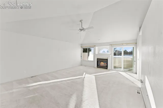 a view of an empty room with window and a kitchen