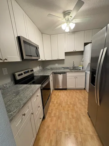 a kitchen with stainless steel appliances granite countertop a sink stove a refrigerator a microwave oven with cabinets and wooden floor