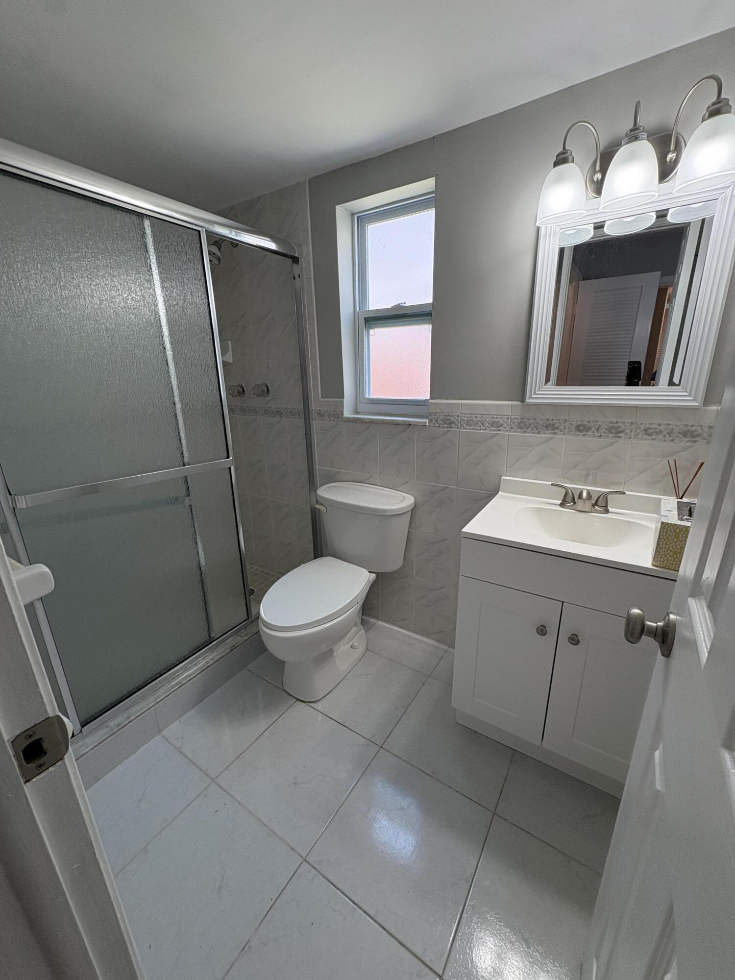 102 Stratford H, Unit A West Palm Beach, FL 33417 - Photo 2 of 19 a bathroom with a sink a toilet a mirror and shower