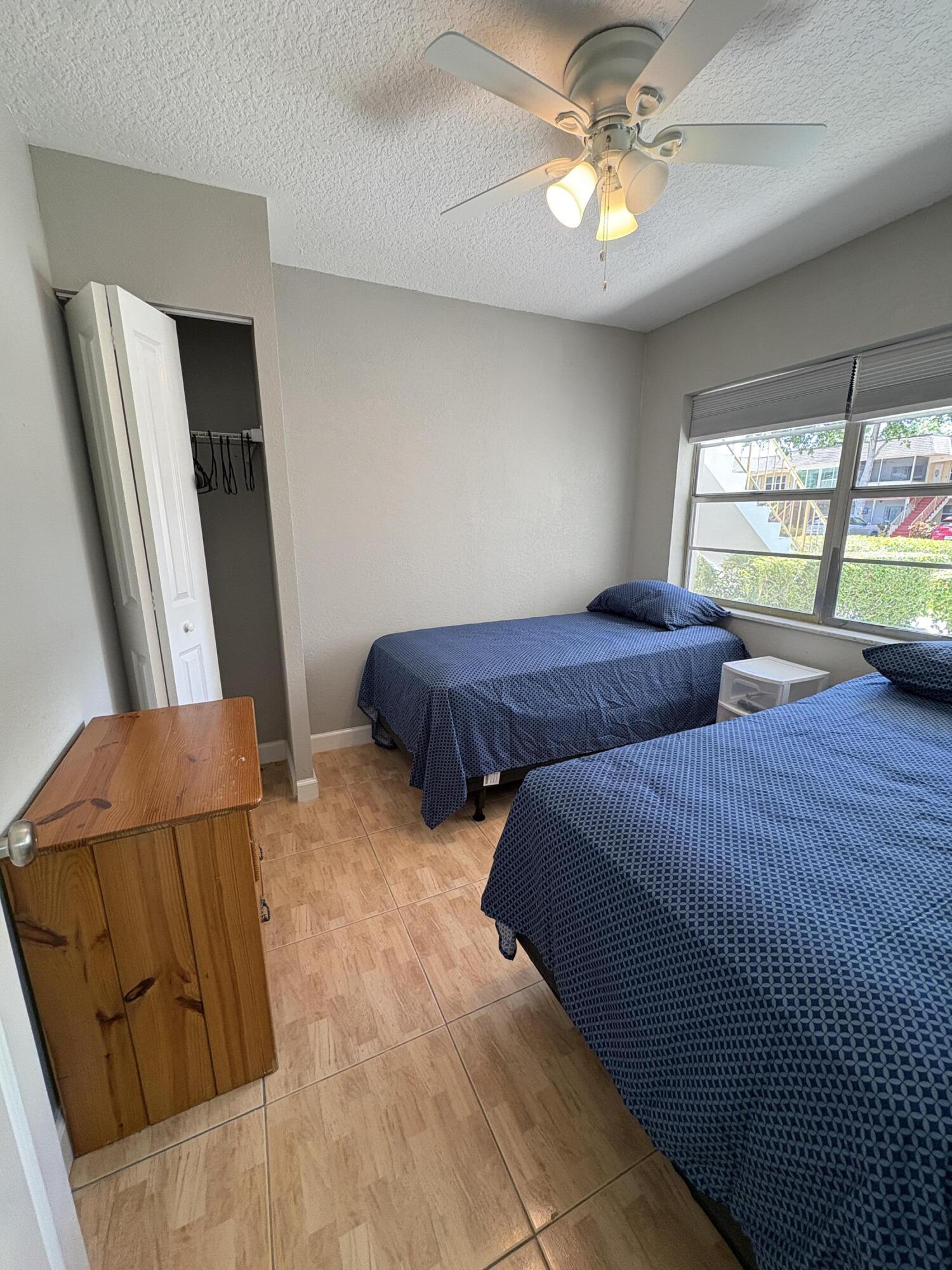 102 Stratford H, Unit A West Palm Beach, FL 33417 - Photo 3 of 19 a bedroom with two beds and a chandelier