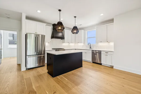 a kitchen with a refrigerator a sink and wooden floor