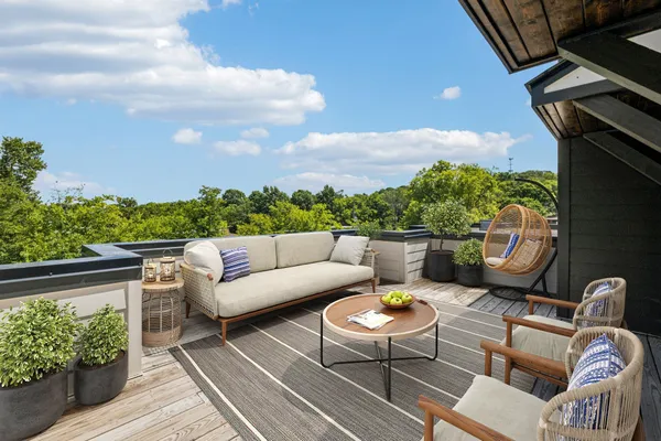 a view of roof deck with couches and potted plants