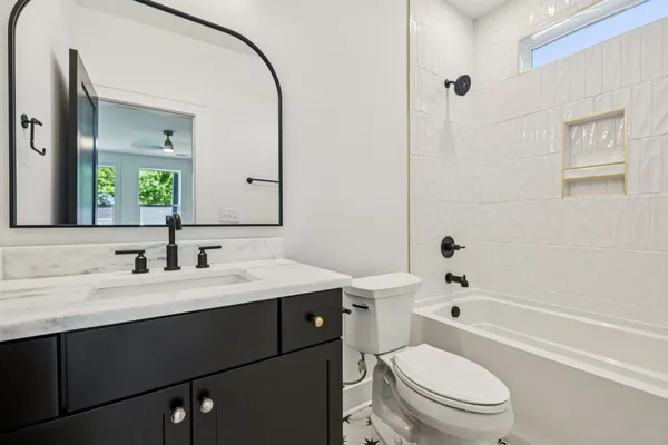 a bathroom with a toilet a sink a mirror a bathtub and vanity