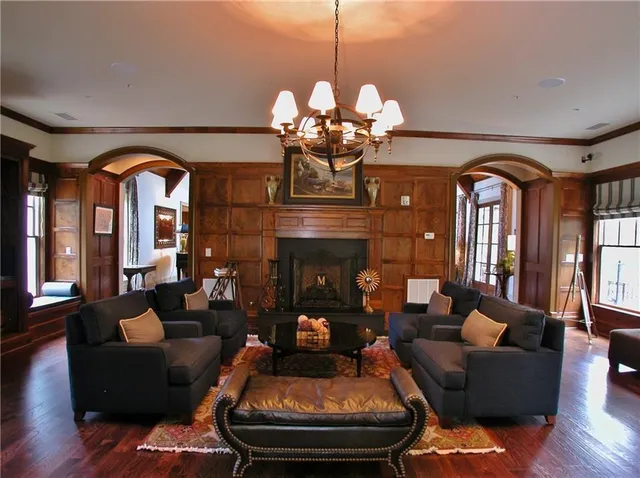 a living room with couches a fireplace and a chandelier