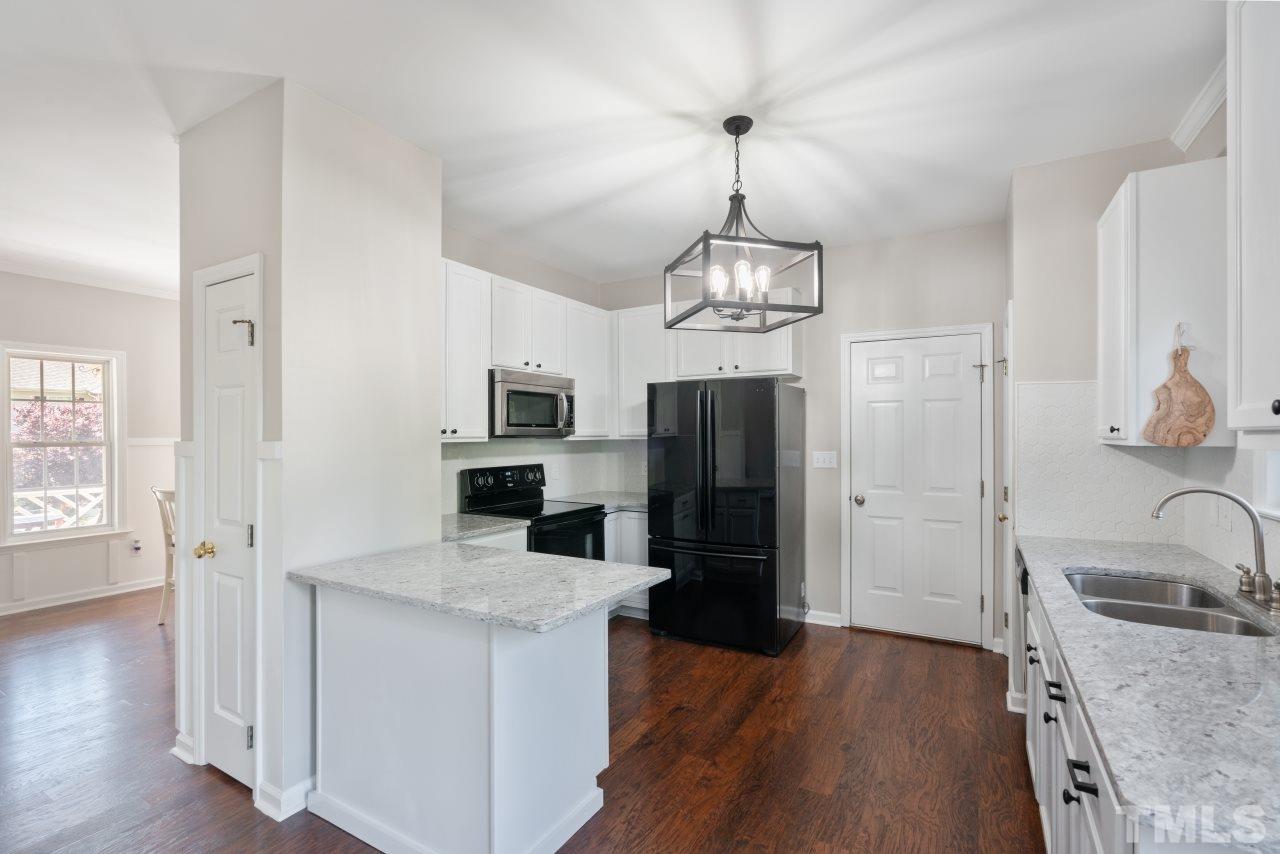 2133 Haig Point Way Raleigh, NC 27604 - Photo 9 of 28 a kitchen with stainless steel appliances granite countertop a refrigerator a stove oven a sink dishwasher and white cabinets with wooden floor