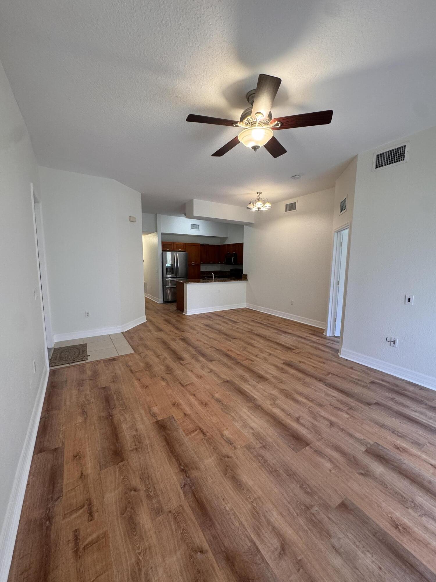 53 Southeast Sedona Circle, Unit 106 Stuart, FL 34994 - Photo 3 of 19 a view of empty room with wooden floor and fan