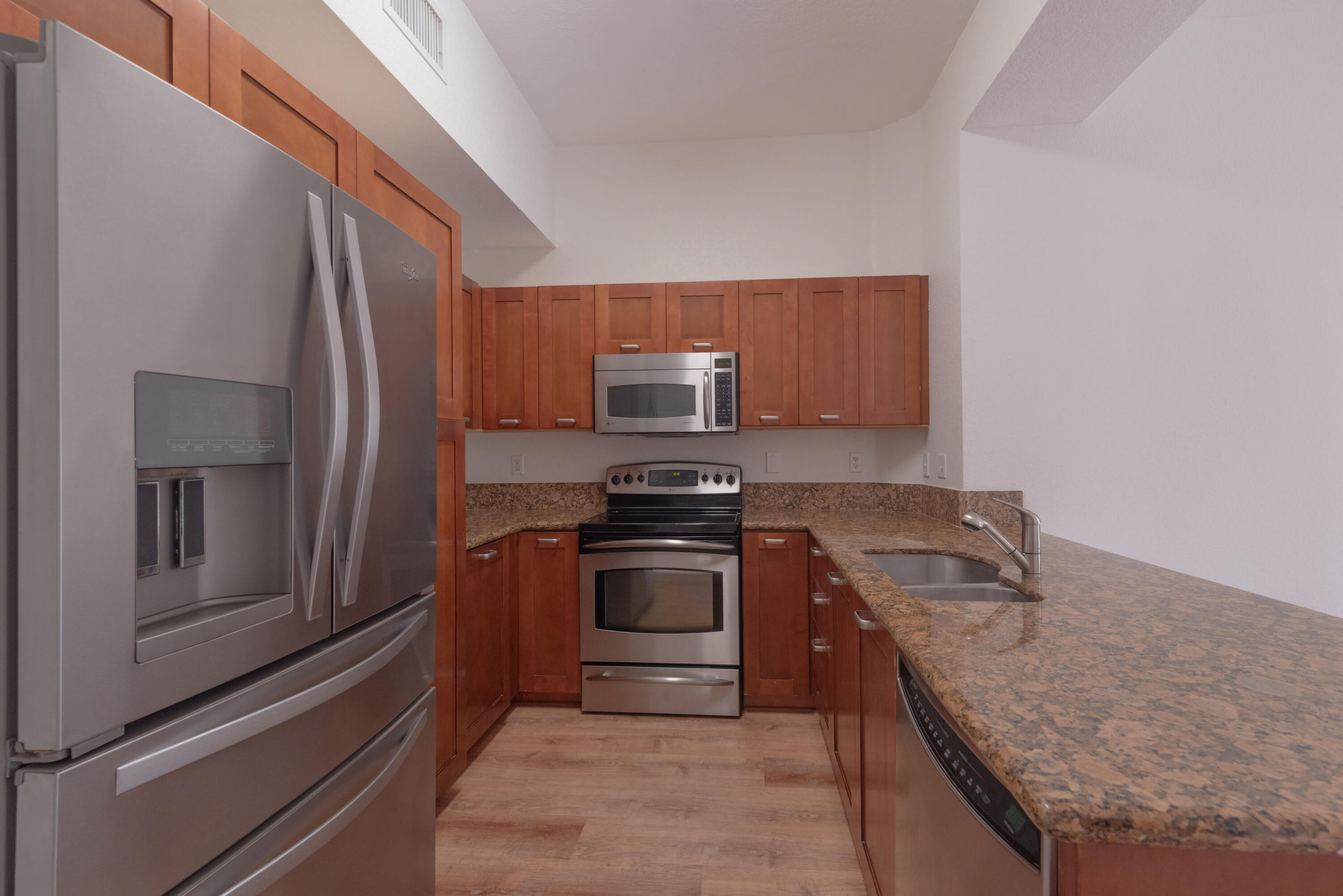 53 Southeast Sedona Circle, Unit 106 Stuart, FL 34994 - Photo 4 of 19 a kitchen with granite countertop stainless steel appliances and wooden cabinets