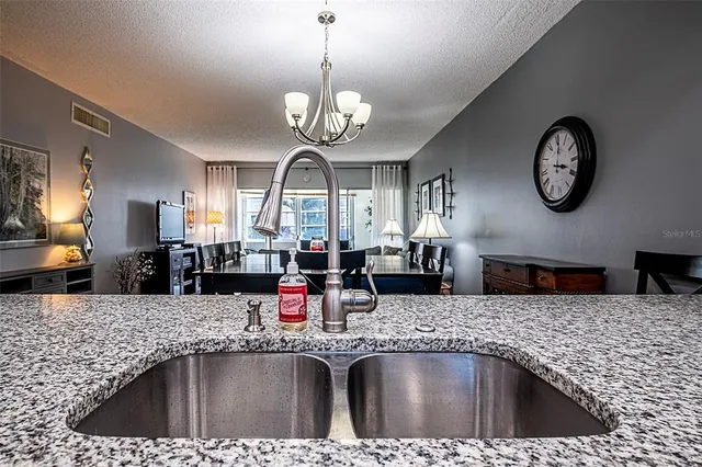 a kitchen with stainless steel appliances granite countertop a sink dishwasher a stove and couches with wooden floor