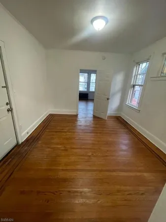 a view of empty room with window and wooden floor