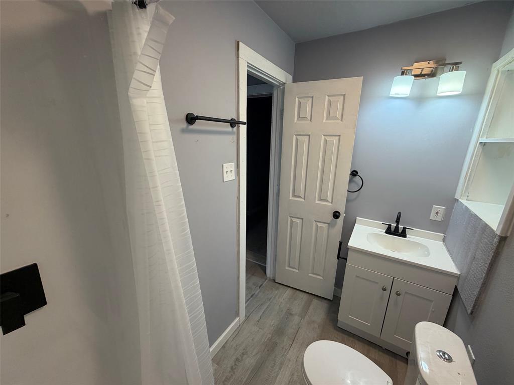 714 Southwest Dallas Street Grand Prairie, TX 75051 - Photo 6 of 27 Bathroom featuring a white vanity with an integrated sink, black faucet, and overhead light fixture