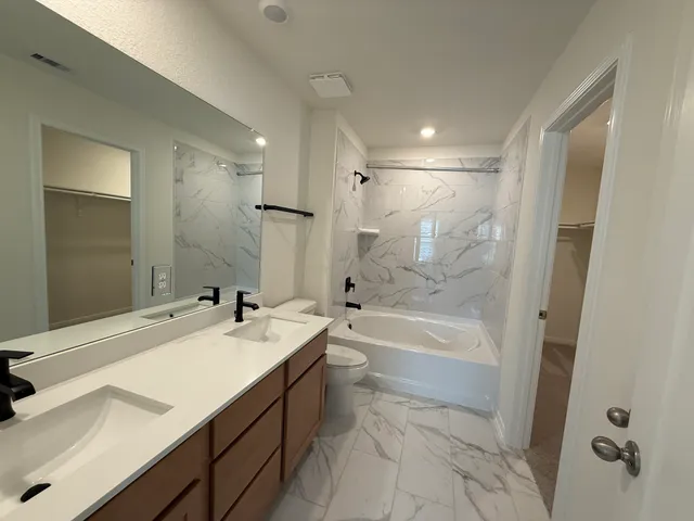 a bathroom with a bathtub shower sink vanity and toilet