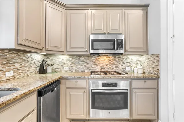 a kitchen with granite countertop white cabinets and stainless steel appliances
