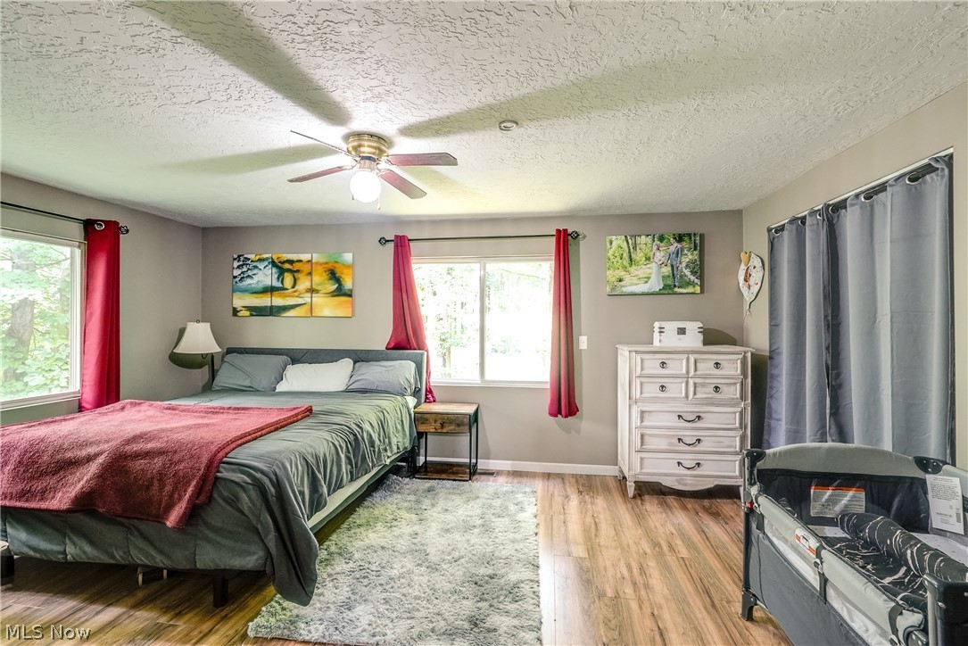 15980 Adams Road Middlefield, OH 44062 - Photo 41 of 49 Bedroom featuring a textured ceiling, multiple windows, light wood-type flooring, and ceiling fan