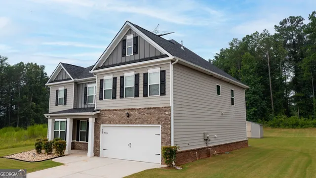 a view of a white house next to a yard with big trees