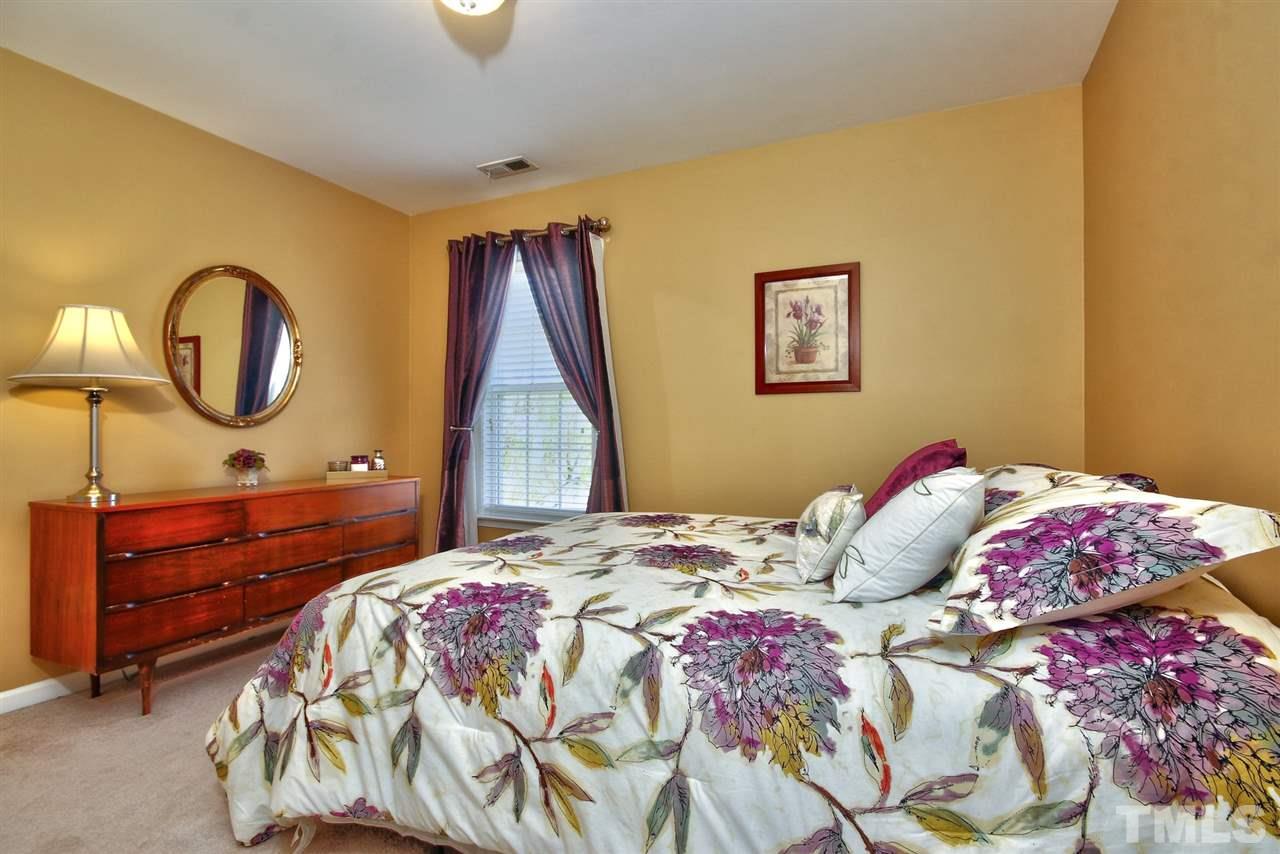 7616 Derek Drive Raleigh, NC 27613 - Photo 20 of 25 a bedroom with a bed and a chandelier