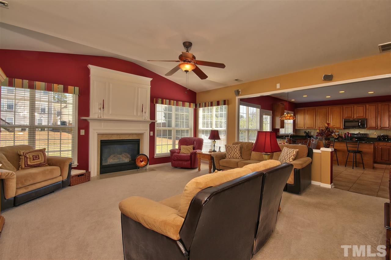 7616 Derek Drive Raleigh, NC 27613 - Photo 7 of 25 a living room with furniture a fireplace and a flat screen tv