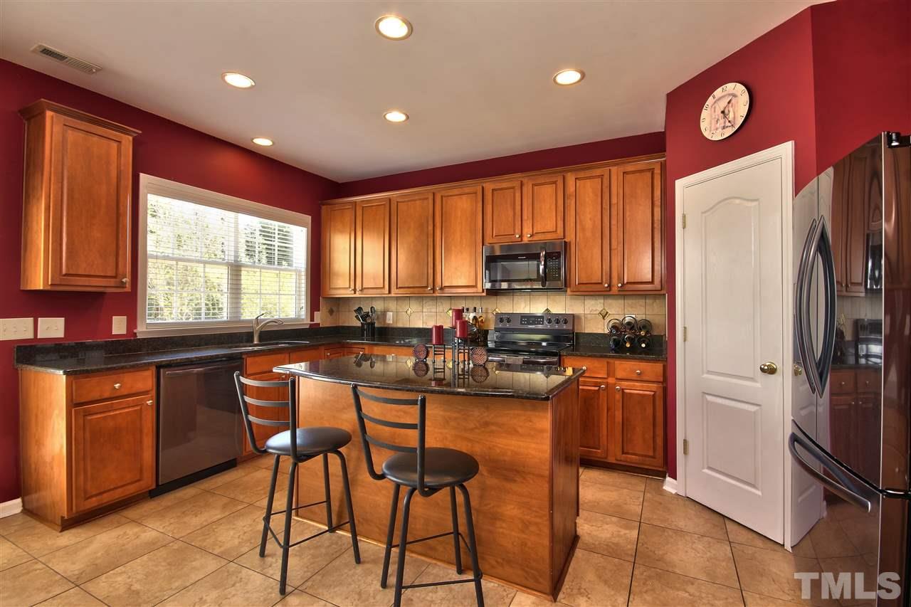 7616 Derek Drive Raleigh, NC 27613 - Photo 8 of 25 a kitchen with stainless steel appliances granite countertop a refrigerator a sink dishwasher a stove a dining table and chairs with wooden floor