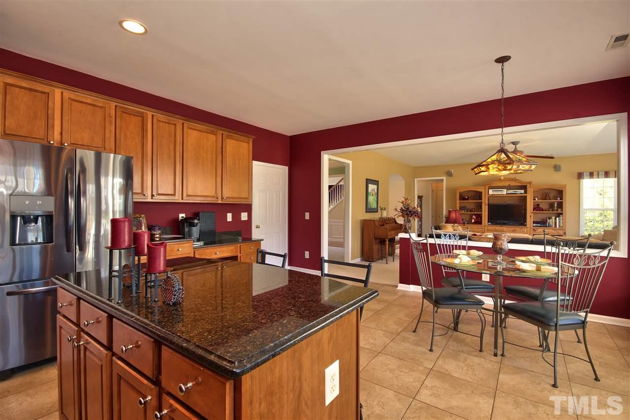 7616 Derek Drive Raleigh, NC 27613 - Photo 9 of 25 a kitchen with granite countertop a table chairs microwave and refrigerator