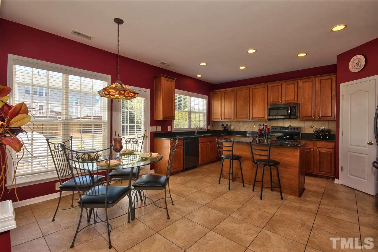 7616 Derek Drive Raleigh, NC 27613 - Photo 10 of 25 a kitchen with stainless steel appliances kitchen island granite countertop a stove a refrigerator a oven a sink with a dining table and chairs