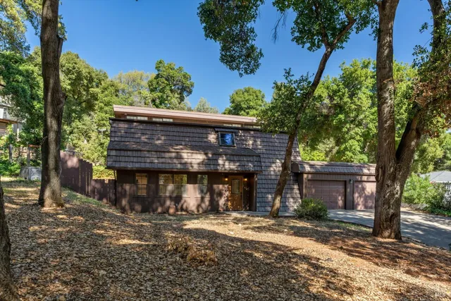 a front view of a house with a tree