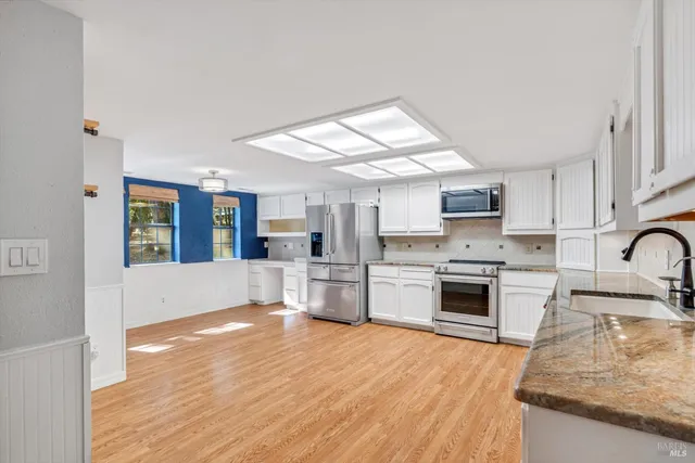 a large kitchen with cabinets wooden floor and stainless steel appliances