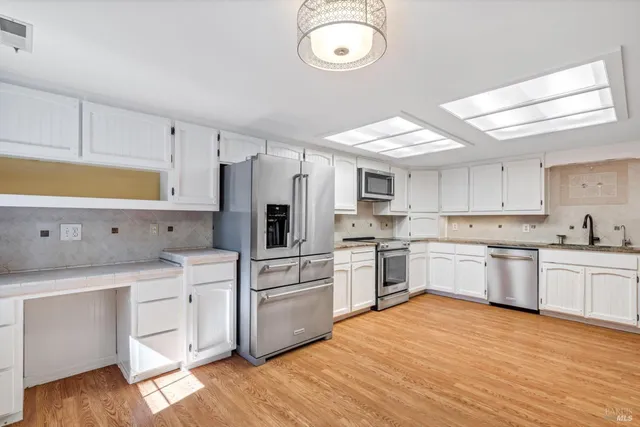 a kitchen with white cabinets stainless steel appliances and wooden floor