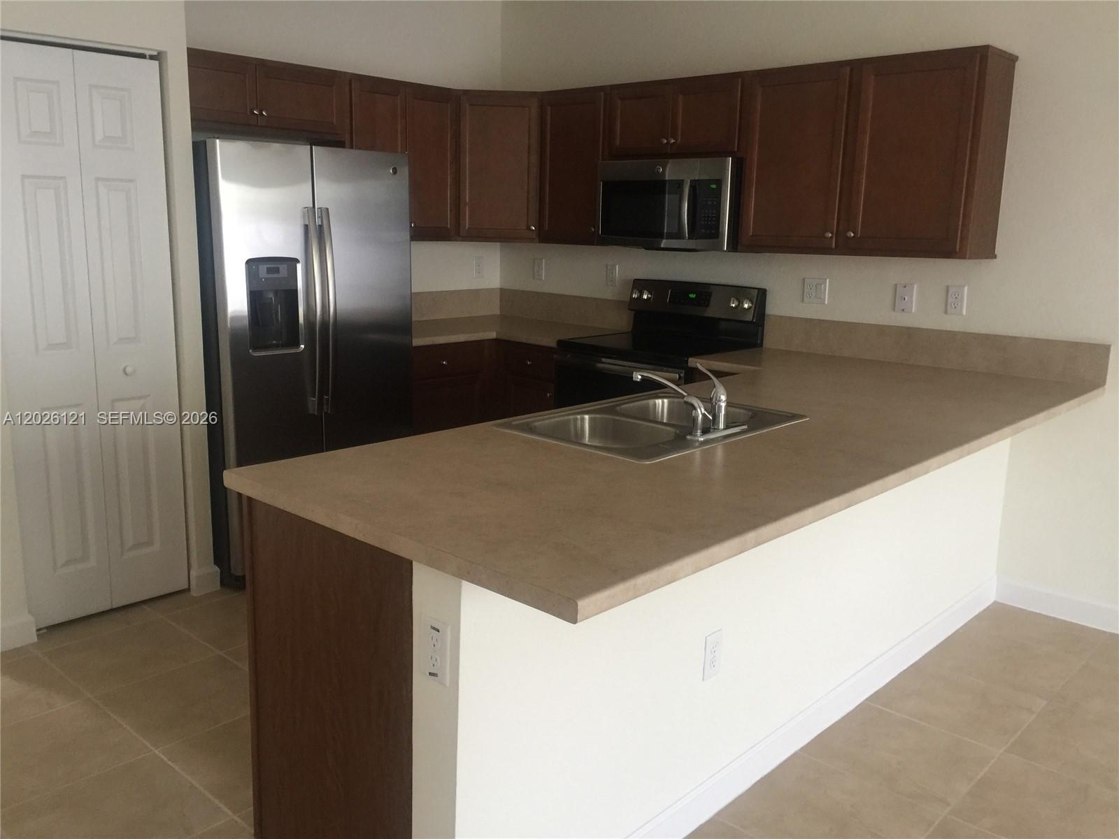 9307 West 33rd Way Hialeah, FL 33018 - Photo 7 of 23 a kitchen with stainless steel appliances granite countertop a sink microwave and refrigerator