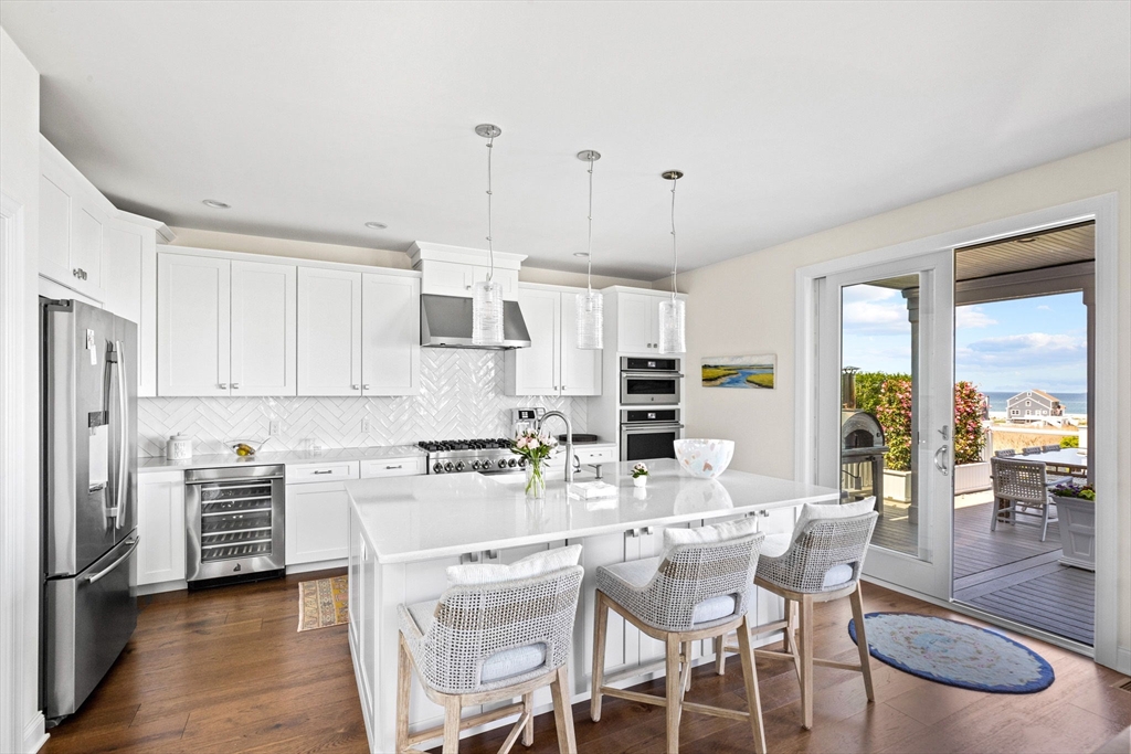 148 Hatherly Road, Unit 148 Scituate, MA 02066 - Photo 14 of 42 a kitchen with stainless steel appliances kitchen island granite countertop a stove a refrigerator a sink a dining table and chairs with wooden floor