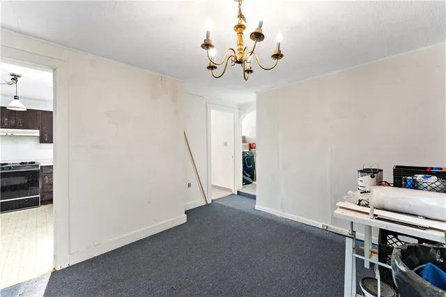 a view of a room with a baby crib wooden floor and a chandelier