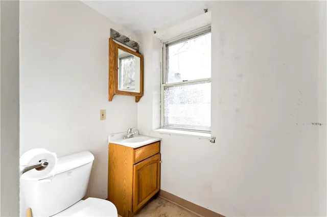 a bathroom with a toilet a sink a mirror and a window